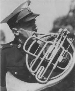 Photo of bandsman Cedric Ashton playing the French horn (WWII)