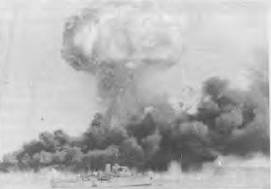 HMAS DELORAINE during the Japanese raid on Darwin, with oil tanks of fire in tbe background